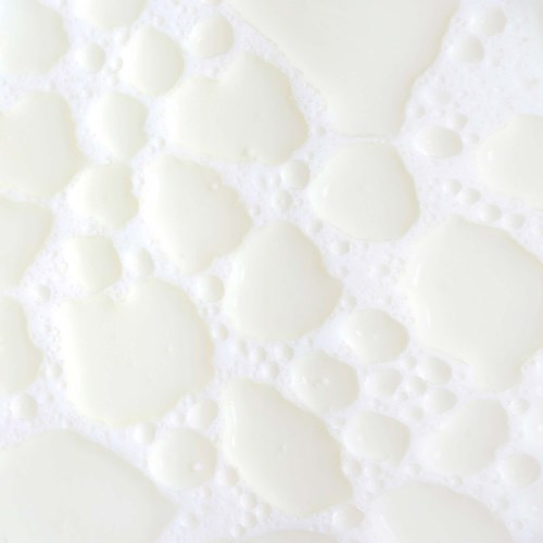 Cremige Flüssigkeit mit Bläschen, ähnlich wie Milch oder Sahne. Keine weiteren Objekte oder Hintergründe sichtbar. Einfach und schlicht.