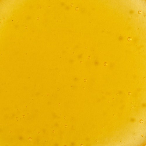 Bubbles in a yellow liquid, with some small dark spots and an uneven surface texture.