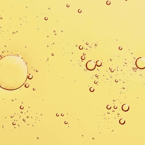 Bubblor i olika storlekar svävar i en gul vätska, vilket skapar en livlig, bubblig scen.