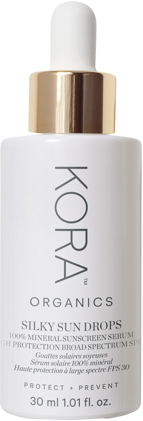 En vit flaska med guldkapsel, märkt KORA Organics Silky Sun Drops mineral solkrämserum, 30 ml.