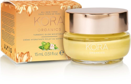 Słoik z żółtym kremem na twarz z złotą pokrywką i pasującym pudełkiem, oznakowany 'KORA Organics' i 'Turmeric Glow Moisturizer.'