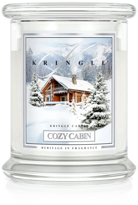 En vintrig scene med en koselig hytte omgitt av snøklare trær, på et lys med merket 'Cozy Cabin' av Kringle Candle.