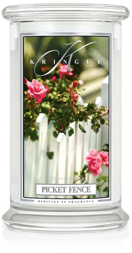 Et stearinlys med blomsterdesign og etiket til Picket Fence duft, viser pink blomster og et hvidt hegn.