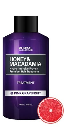 A purple shampoo bottle labeled for honey and macadamia hair treatment, with a pink grapefruit slice beside it.