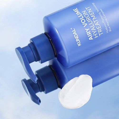 Two blue bottles of hair therapy shampoo with a dollop of white cream or shampoo near them.