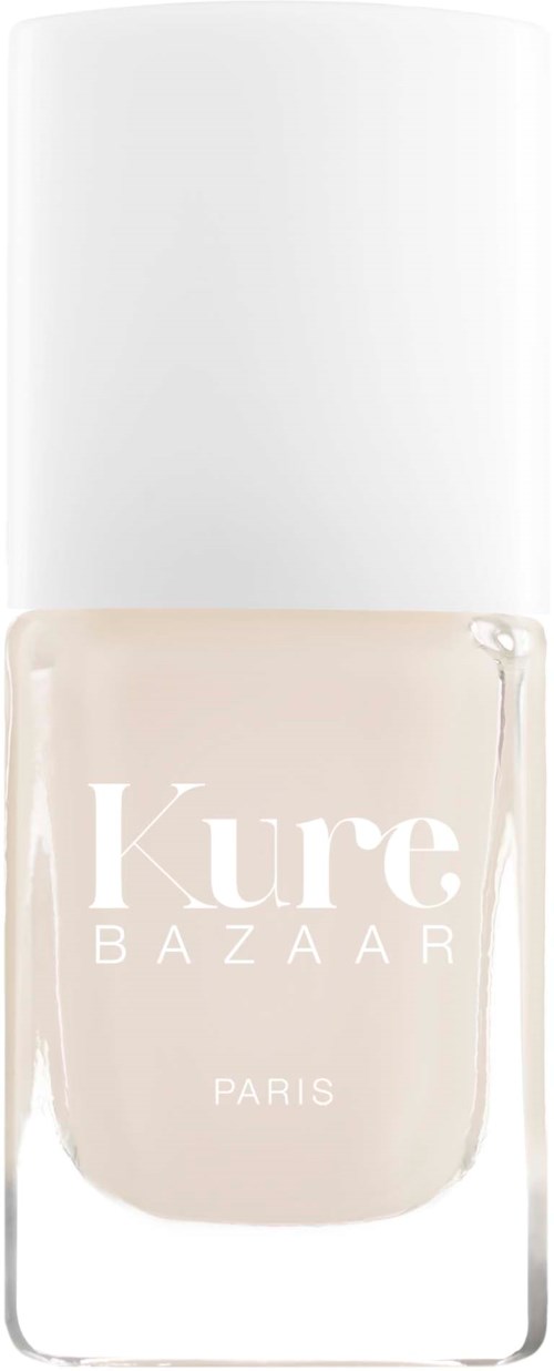 En nagellackflaska med vit lock och ljusbeige färg. Etiketten säger 'Kure Bazaar Paris'.