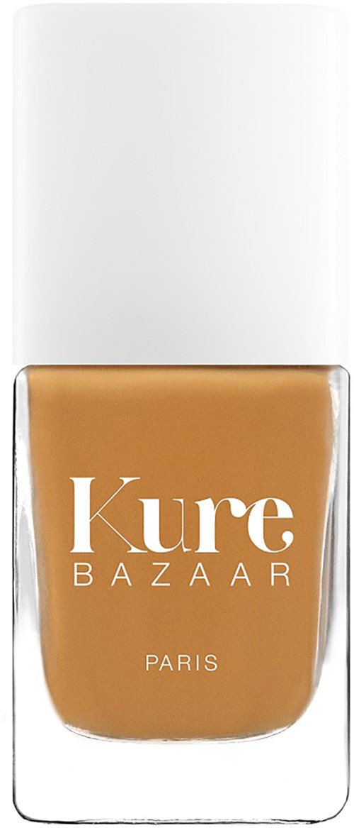 Een nagellakfles met een witte dop, gelabeld 'Kure BAZAAR PARIS' in witte tekst op een lichtbruin lakje.