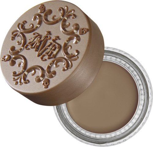 En rund behållare med ett dekorativt lock som har ordet 'Art' och swirl-designs, fylld med beige kräm.