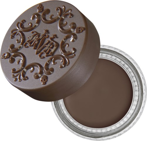 En rund, brun kosmetikkförpackning med dekorativa upphöjda bokstäver på locket, fylld med brun kräm.