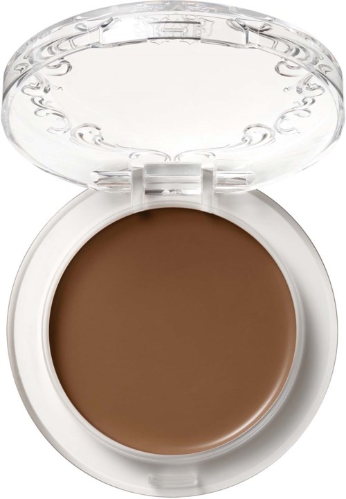 Et brunt makeupprodukt i en rund hvit beholder med gjennomsiktig lokk.