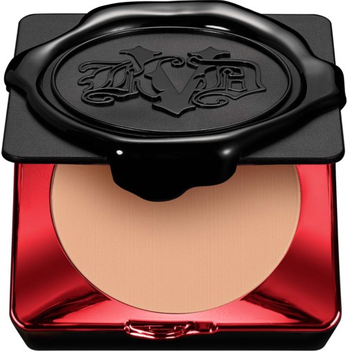 En makeup-kompakt i rött och svart fall, med pressat puder och ett dekorativt lock med en logotypdesign.