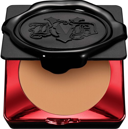En makeup-kompakt med svart lock och röd botten, innehållande beige puder.
