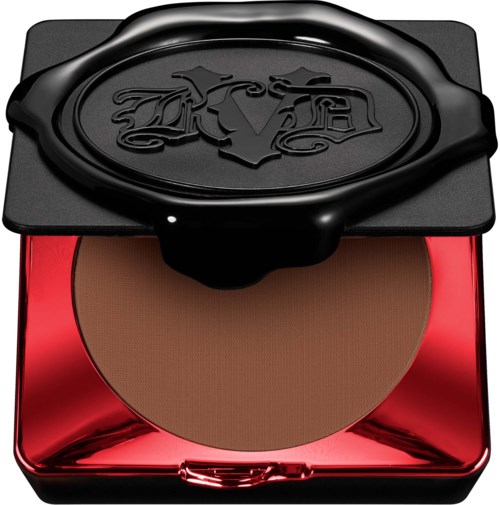 En liten makeup-puder i en röd och svart fyrkantig behållare med lock, med en logotypdesign.
