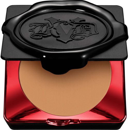 En liten makeup-puder med svart lock som har en logotyp och ett glänsande rött skal under.