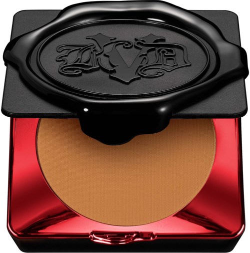 En liten makeuppuderbehållare med svart lock och en röd, blank bas.