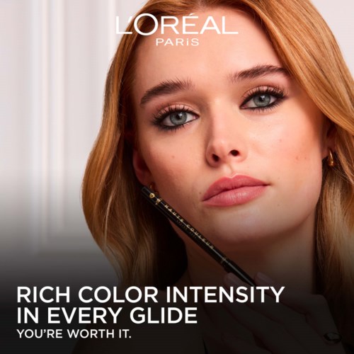 Młoda kobieta z czerwonymi włosami patrzy na aparat, logo L'Oréal Paris i tekst promocyjny o farbach do włosów.