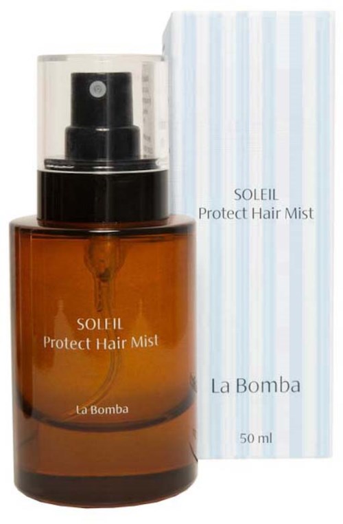 Brązowa butelka z rozpylaczem Soleil Protect Hair Mist z przezroczystym korkiem, obok białe i niebieskie paskowane pudełko.