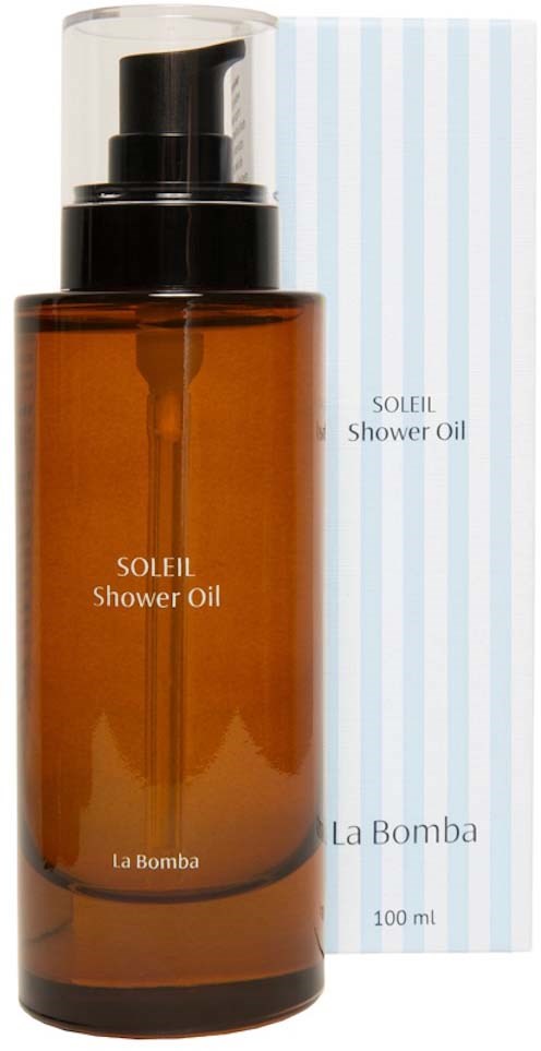 Brązowa butelka Soleil Shower Oil z czarnym dozownikiem i niebiesko-białym paskowanym opakowaniem w tle.