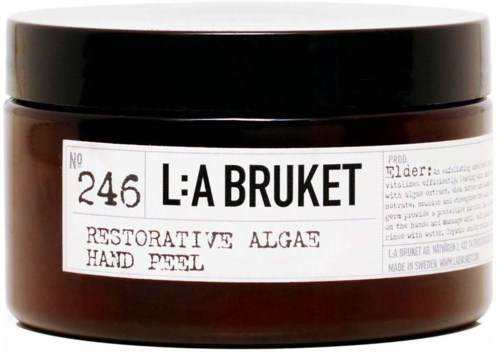 A jar labeled La Bruket, containing restorative algae hand peel, with a black lid and white label, placed against a black background.