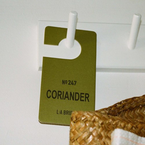 A green label hanging from a white rack, with the number 247 and the word 'Coriander' on it.