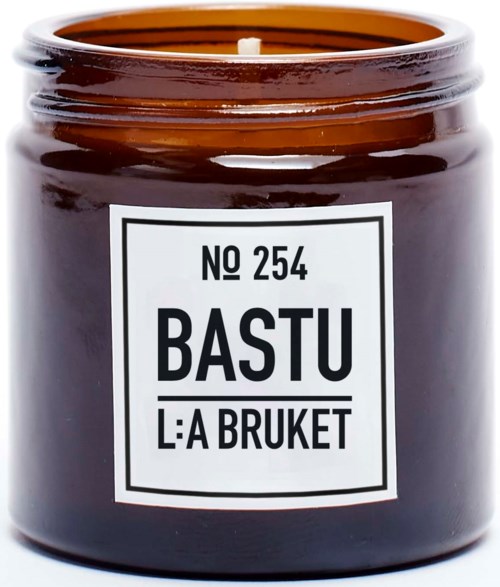 Ein brauner Kerzenglas mit weißem Etikett, das 'No 254 BASTU L:A BRUKET' in schwarzem Text zeigt.