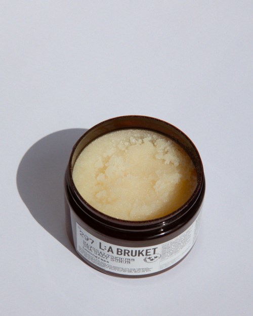 A brown jar labeled 'LÅ BRUKET' contains a creamy, pale yellow substance, likely a skincare product or body butter.