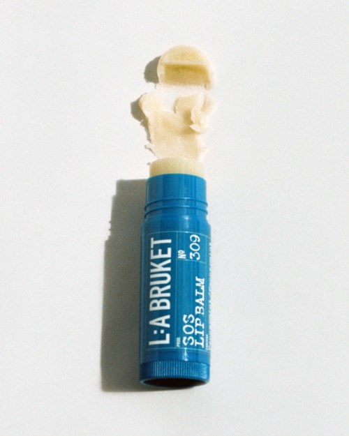 A blue lip balm stick with white cream coming out and some cream placed on top.