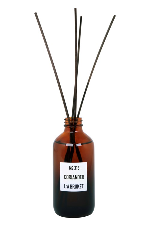 A brown glass bottle with a label and several thin sticks or reed diffusers inside it.