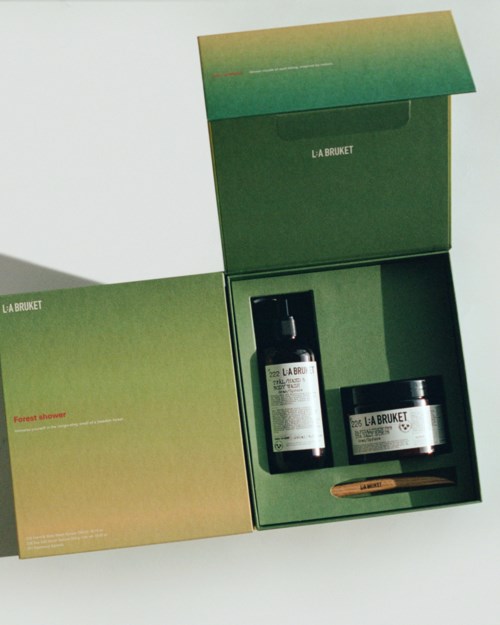 A skincare set includes a bottle, a jar, and a small spatula inside a green box, labeled 'LA BRUKET.'