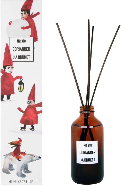 En brun diffuserflaske mærket Nr 318 Koriander fra L:A Bruket med pinde til duft. Illustration af nisser og en hund på emballagen.