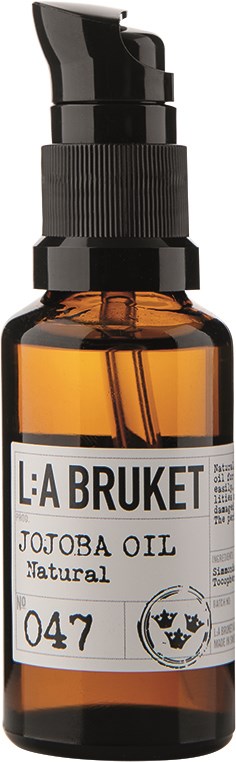 En liten bärnstensfärgad flaska med svart pump märkt 'Jojoba Oil Natural' från La Bruket.