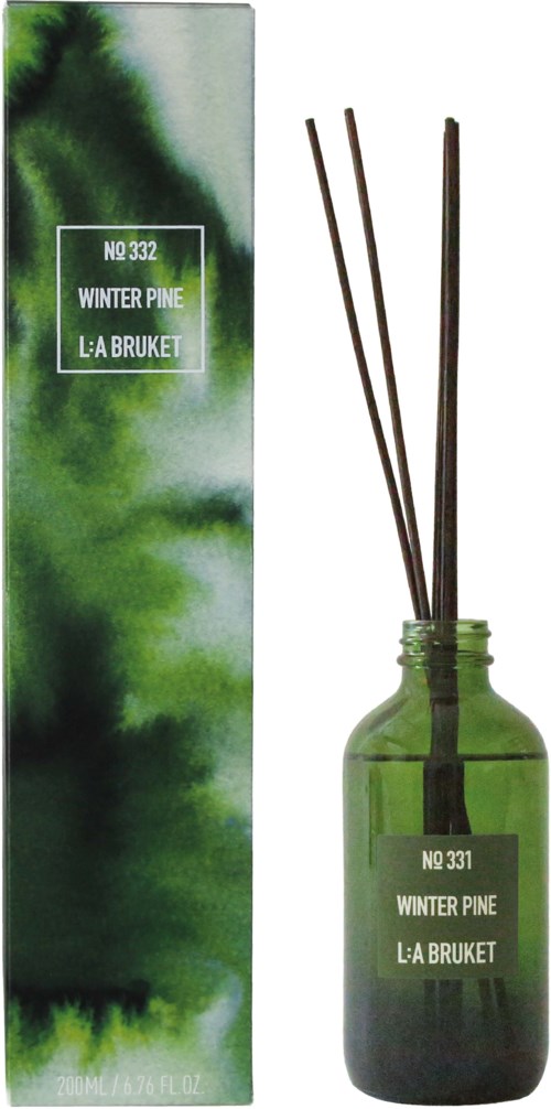 Vihreä lasinen diffuusipullo ja sen paikallaan olevat tikut, merkitty Winter Pine La Bruketilta, ja tämän pakkaus.