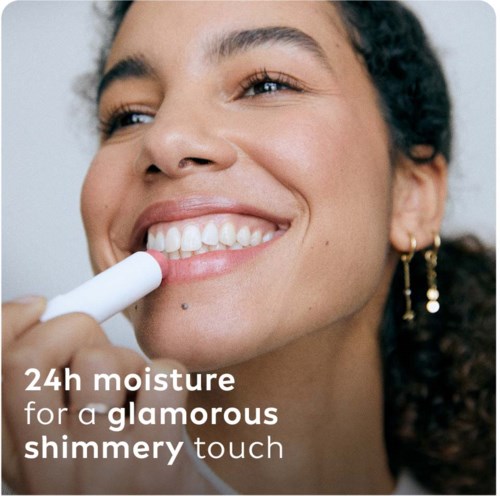 A woman applies lipstick and smiles, promoting 24-hour moisture for a glossy, shiny look.
