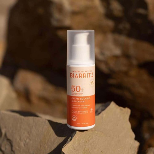 Eine Flasche Biarritz Sonnencreme mit SPF 50 auf einer felsigen Oberfläche im Freien.