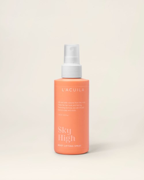 En persikfärgad flaska med vit spraypump, märkt 'L'ACULA Sky High Root Lifting Spray.'