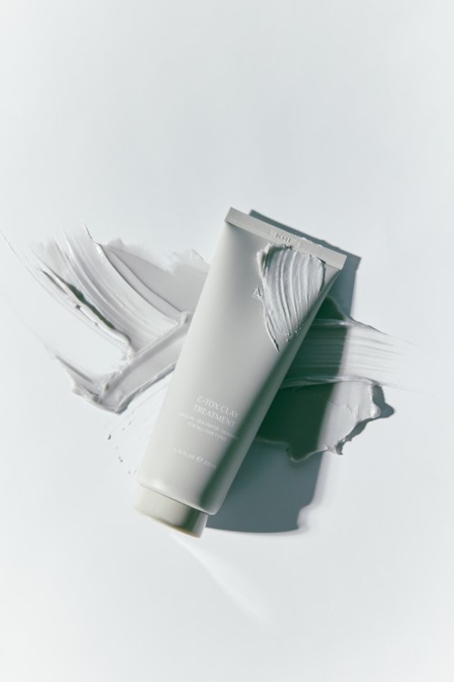A white tube with cream or lotion, some of it spread around on a white surface.