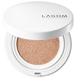 En rund gammaldags kompakt med beige tonad puder inuti och ett vitt lock märkt 'LAGOM'.