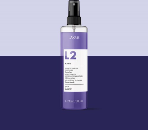 En flaske Lakme L2 Blonde Instant Detangling Conditioner med sprayhette. Lilla og hvit etikett. To-tone bakgrunn.