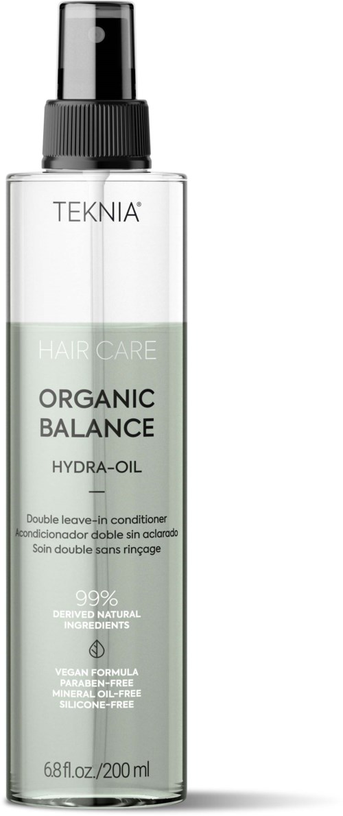 En klar plastflaske med sort pumpe, merket 'TEKNIA' og 'ORGANIC BALANCE HYDRA-OIL', inneholder hårpleieolje.