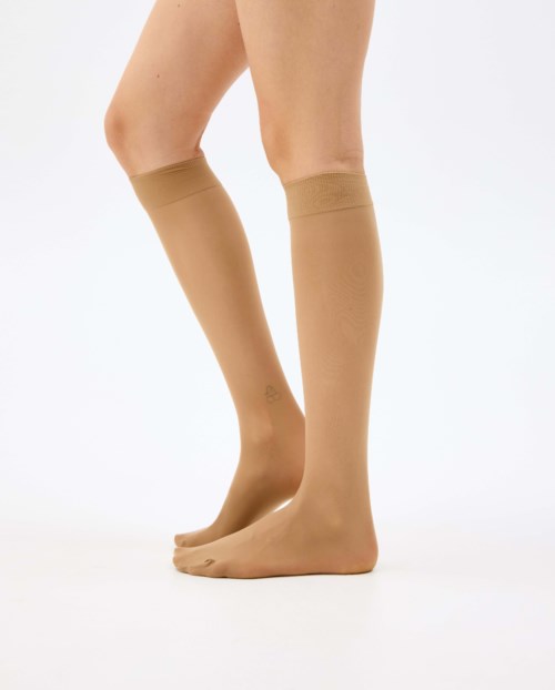 Beige compression stockings or socks worn on legs, extending from feet to knees.