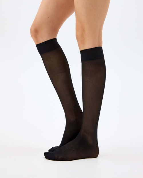 Black knee-high sheer stockings worn on legs, slight bend at the knees, plain white background.