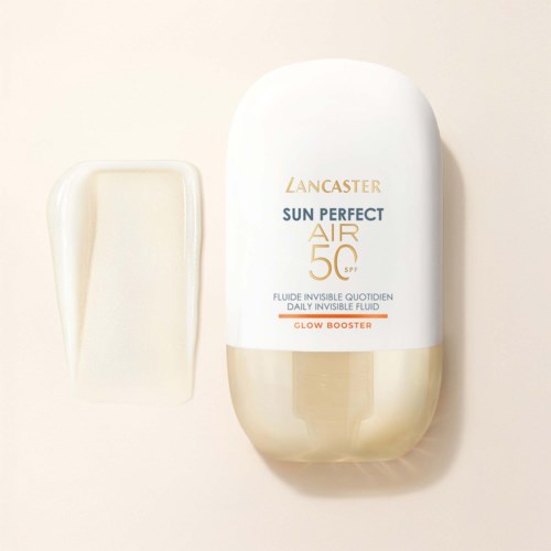 Eine weiße und goldene Flasche von Lancaster Sun Perfect Air SPF 50 mit einem kleinen, cremigen Schwamm daneben.