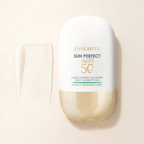 Eine weiße und goldene Flasche Lancaster Sun Perfect Air SPF 50 Sonnencreme mit Text und einem kleinen Fleck Creme daneben.