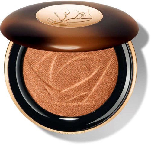 En kompakt puder med glansigt brunt hölje, med en guldig logga på toppen och en texturerad, persikofärgad makeup inuti.