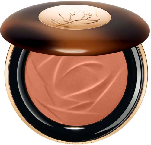 Een ronde make-up compact met een bruine deksel, met beige poeder. Deksel heeft een logo van een liggende vrouw.