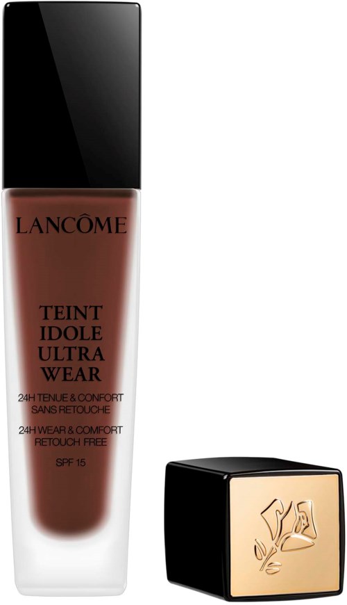 En flaske Lancôme-foundation og en firkantet pude med en guldlogo.