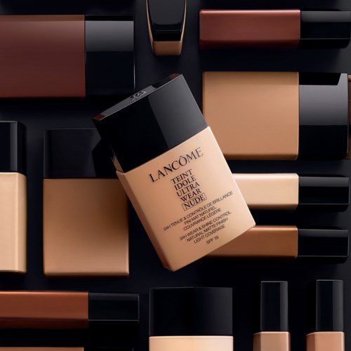 A Lanc4ne makeup foundation bottle surrounded by various makeup products in neutral shades.