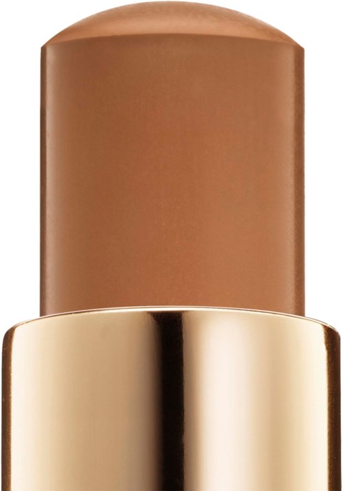 En beige makeup-stift med en blank, guldfarvet hætte, står lodret.