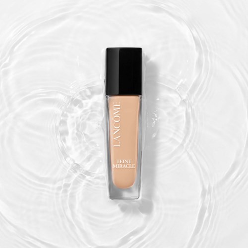 A bottle of Lancôme Teint Miracle foundation floating in water with ripples around it.