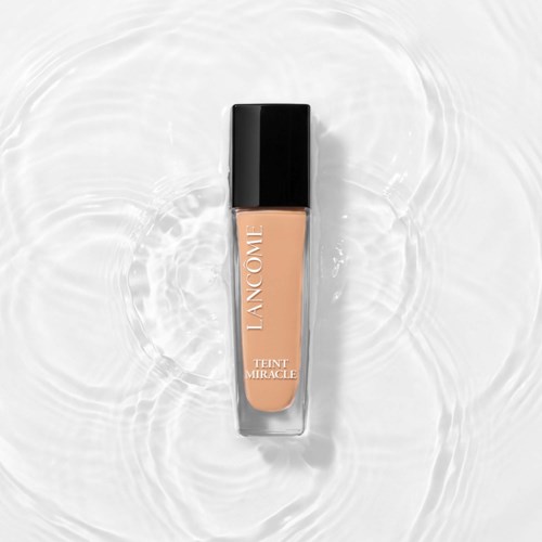 En flaske Lancôme Teint Miracle foundation på vannbølger i bakgrunnen.